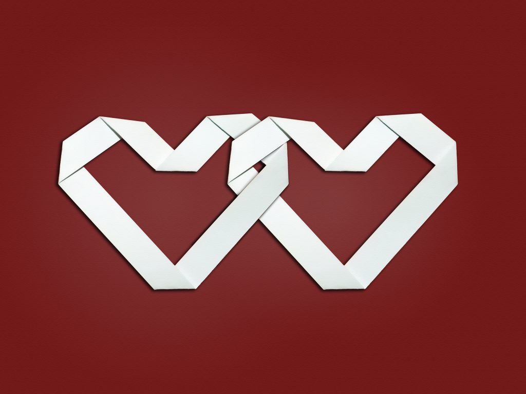 Two matching, interlinked white hearts on a red background.