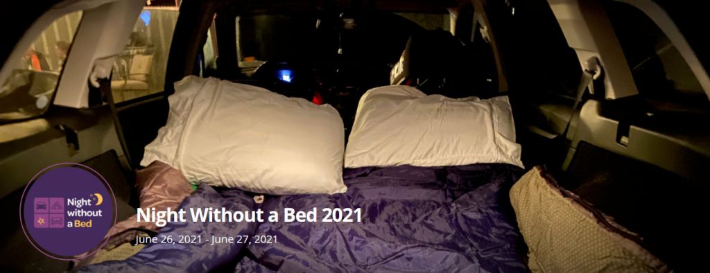 Cover image of the Night Without a Bed Challenge peer-to-peer event. It shows pillows and blankets in the back of someone's vehicle.