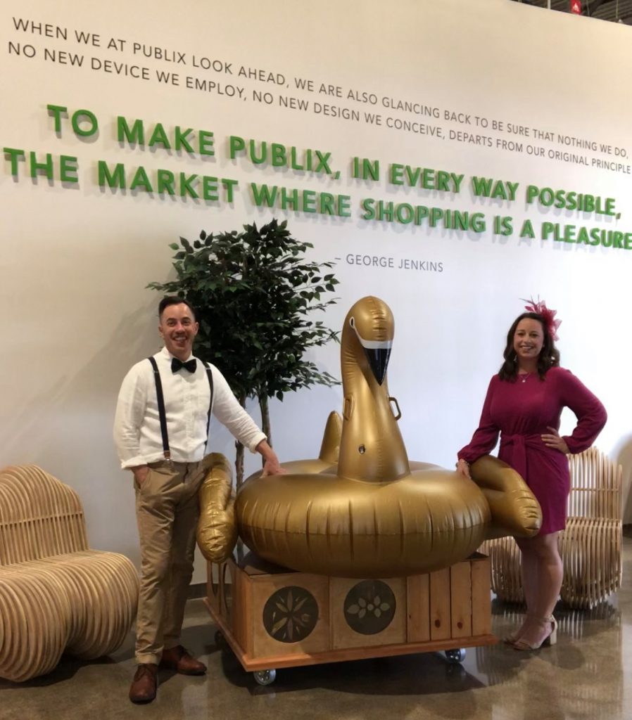 Erin and Damian of Lakeland Volunteers In Medicine's Swan Before the Storm team posing with their golden, inflatable swan raft.