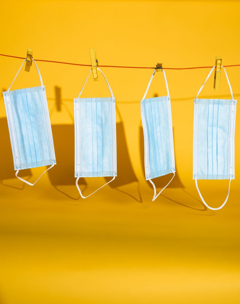 Four disposable surgical masks hanging from a clothesline.