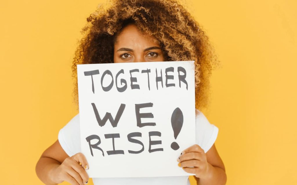 woman holding up a "together we rise" sign