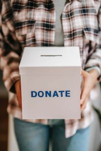 A person holds a white box with the word donate printed on it. 